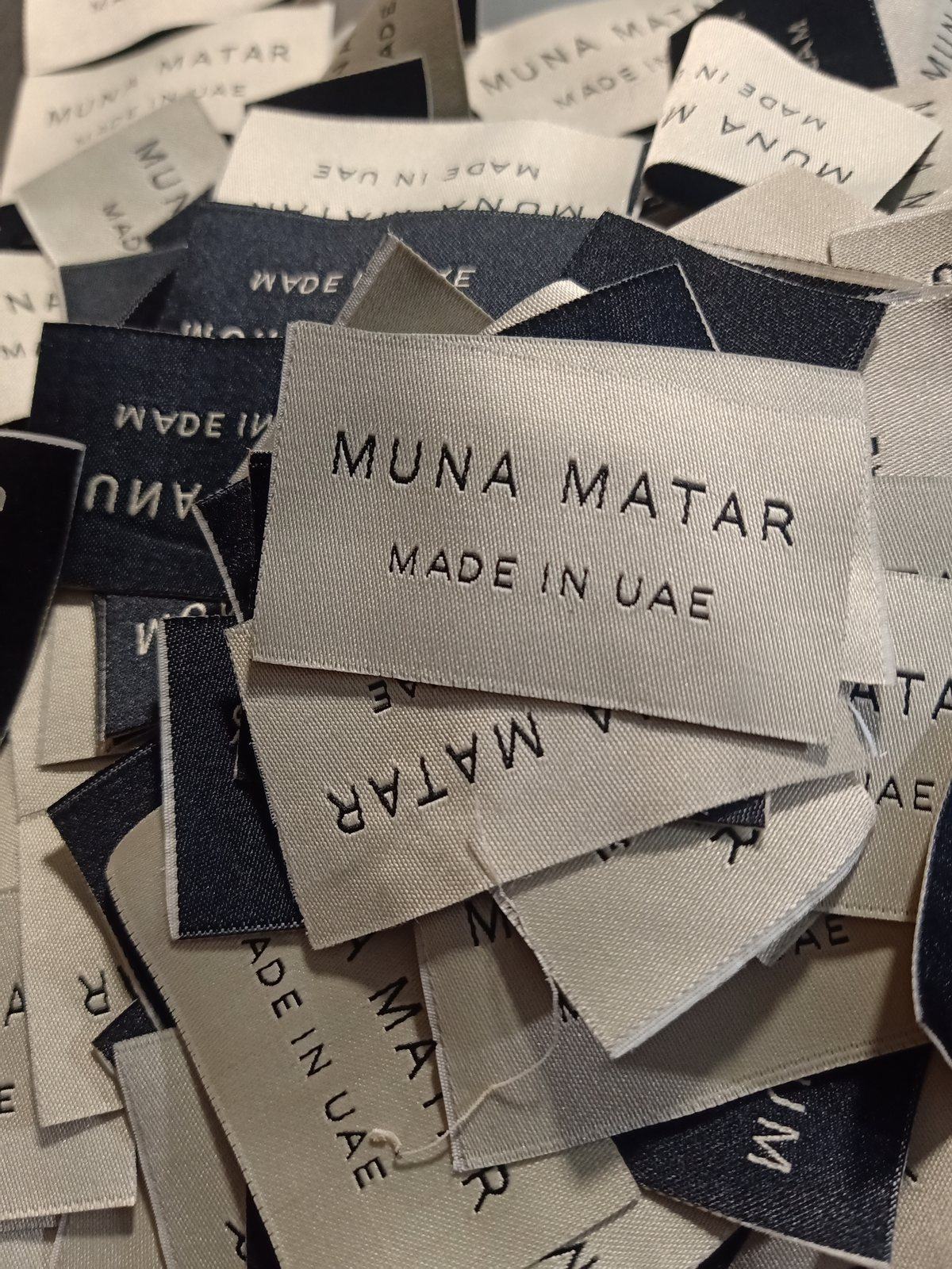 Close-up of a real woven label reading Muna Matar, made in UAE